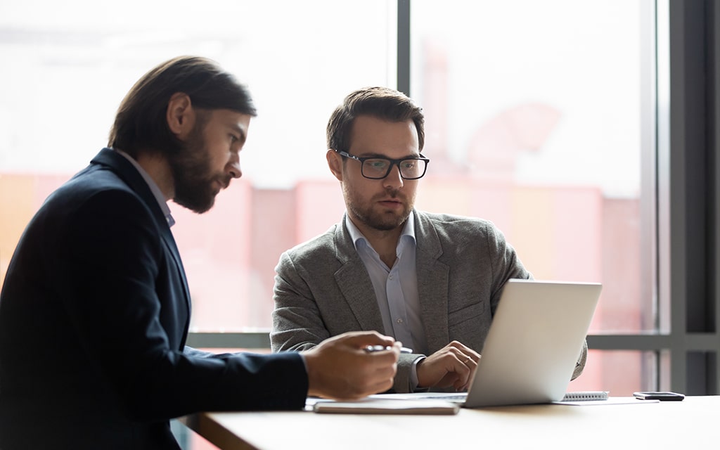 two-businessmen-colleagues-looking-at-laptop-review-min